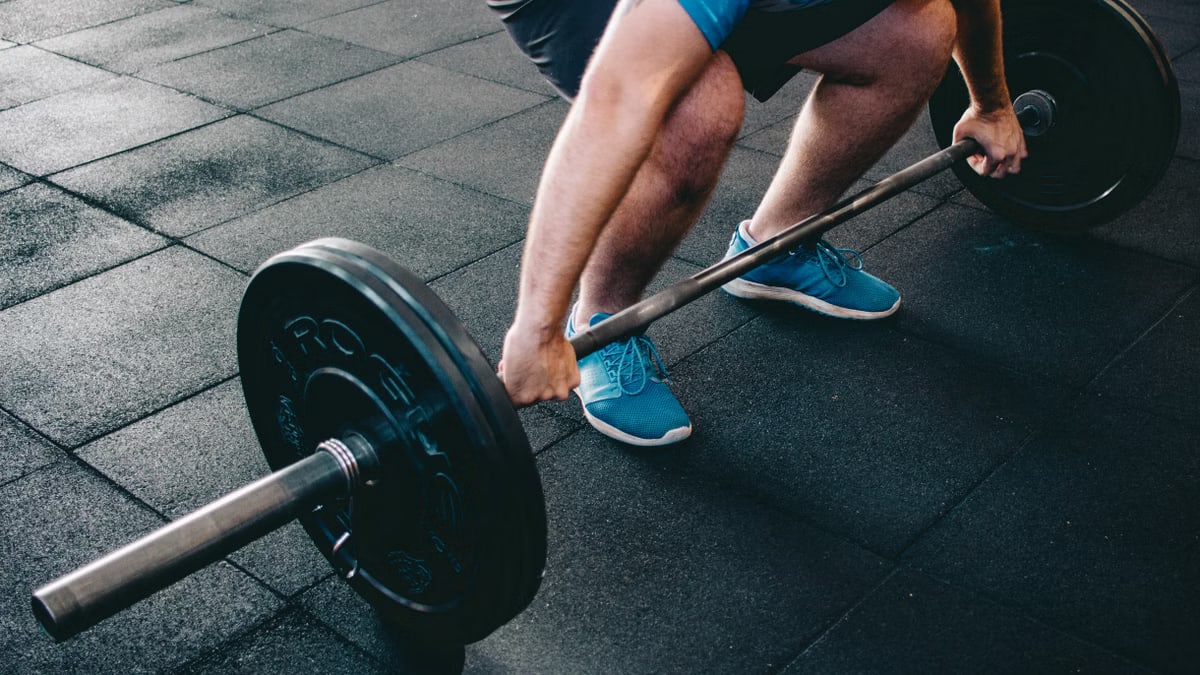 A man deadlifting a barbell indoors showcasing power, fitness, and dedication.